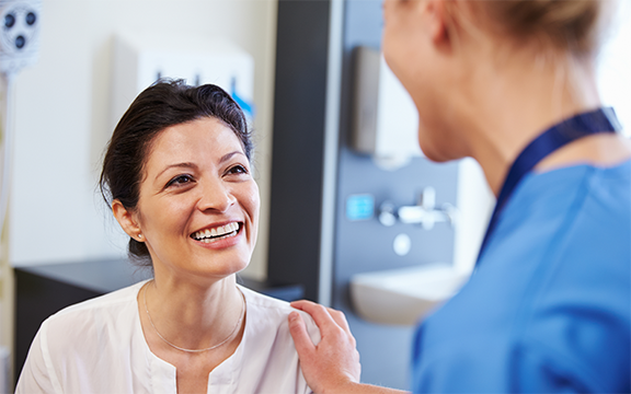 Female Patient Being Reassured By Doctor In Hospital Room