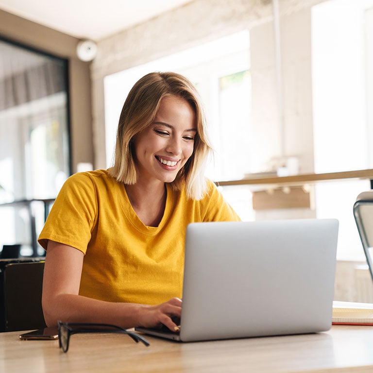 Woman using laptop and smiling while sitting