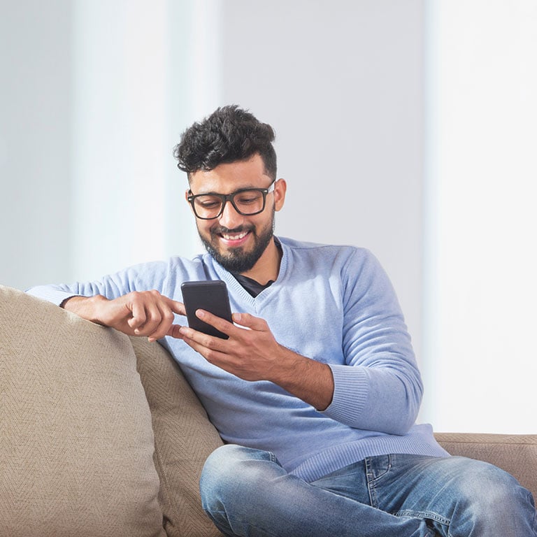Young man sitting on the couch and using his phone