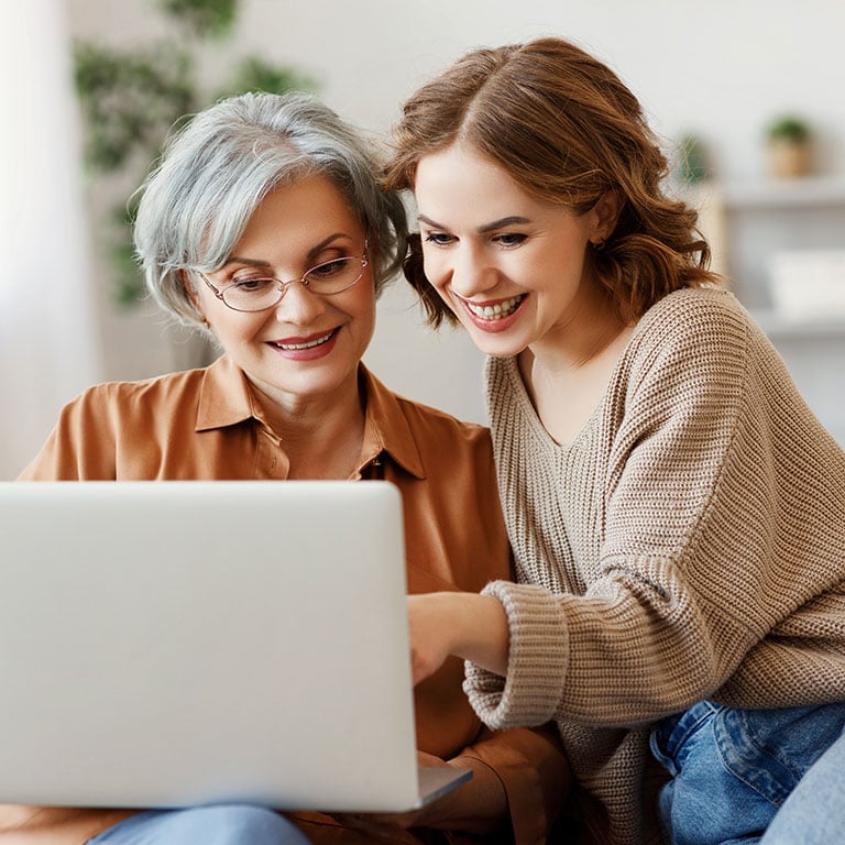 Young woman with mother using laptop at home