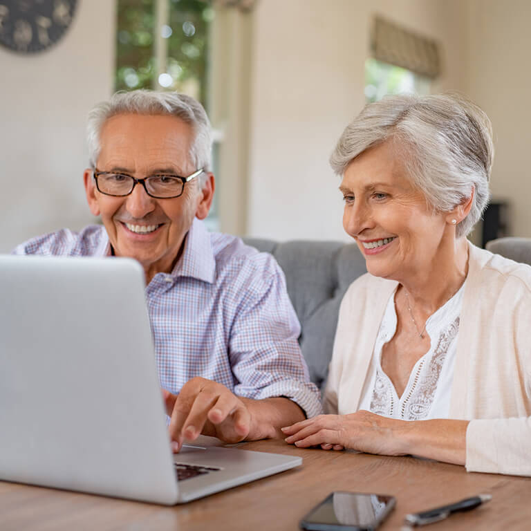 two older adults using a laptop