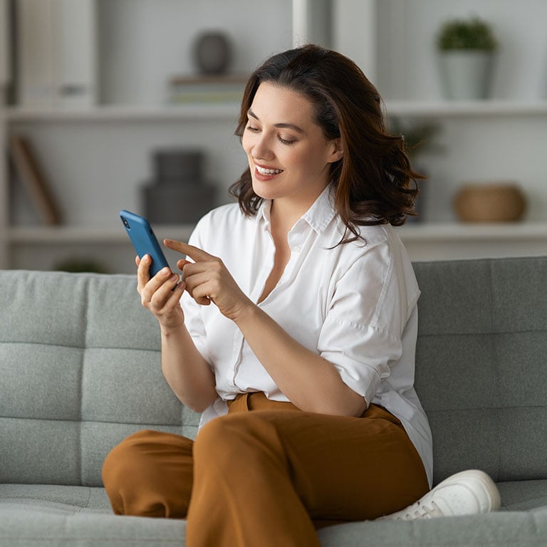 woman sitting on a sofa and using a smartphone