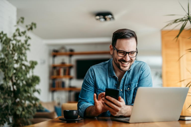 Portrait of a happy man with smart phone and laptop, indoors