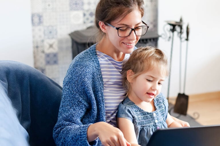 mother on computer while holding child