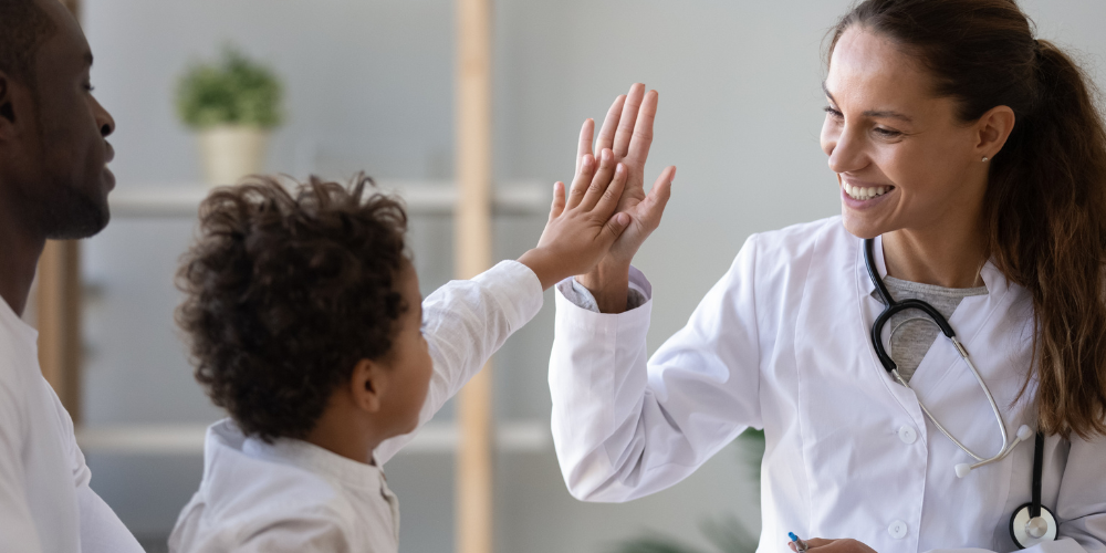 Smiling female doctor give high five to little patient