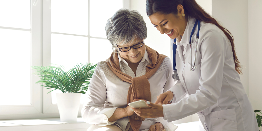 Caring doctor teaches female patient to use mobile healthcare app